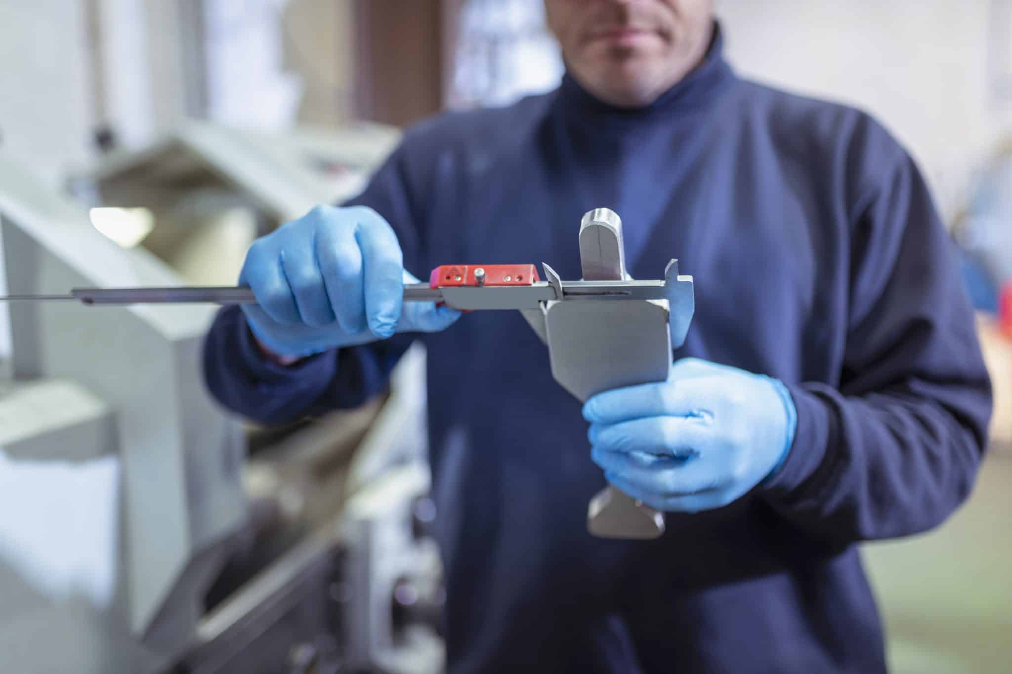 Engineer measuring titanium blanks in industrial forge